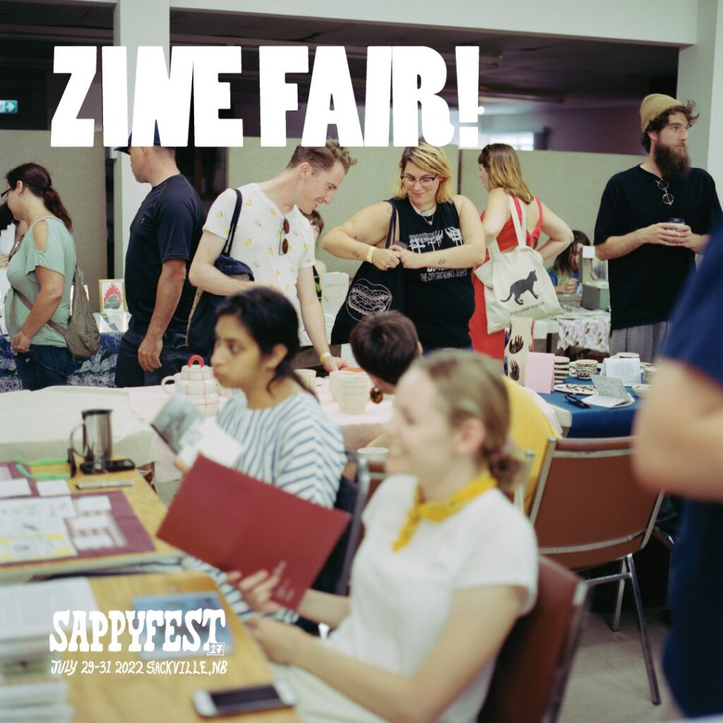 Participants at the zine fair sit at a table.