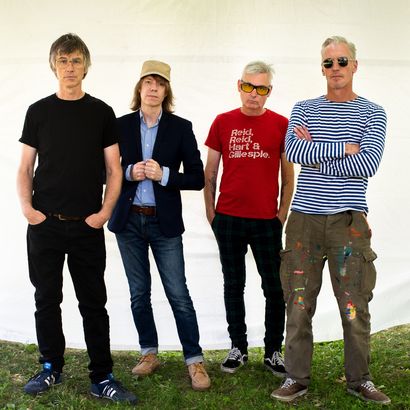 The four members of Sloan stand on grass.