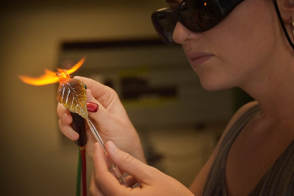 Heather McCaig, wearing protective glasses, works with glass.
